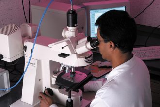Scientist examining samples through a microscope in a laboratory