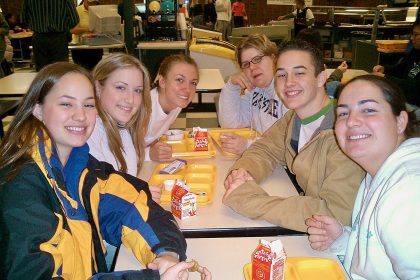 School students eating lunch with fruit in a cafeteria