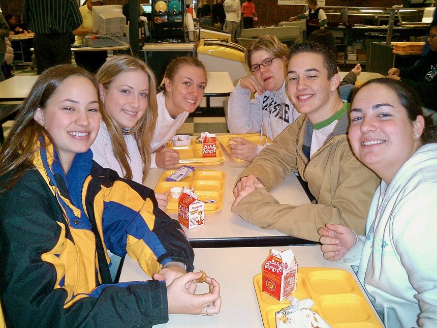 School students eating lunch with fruit in a cafeteria