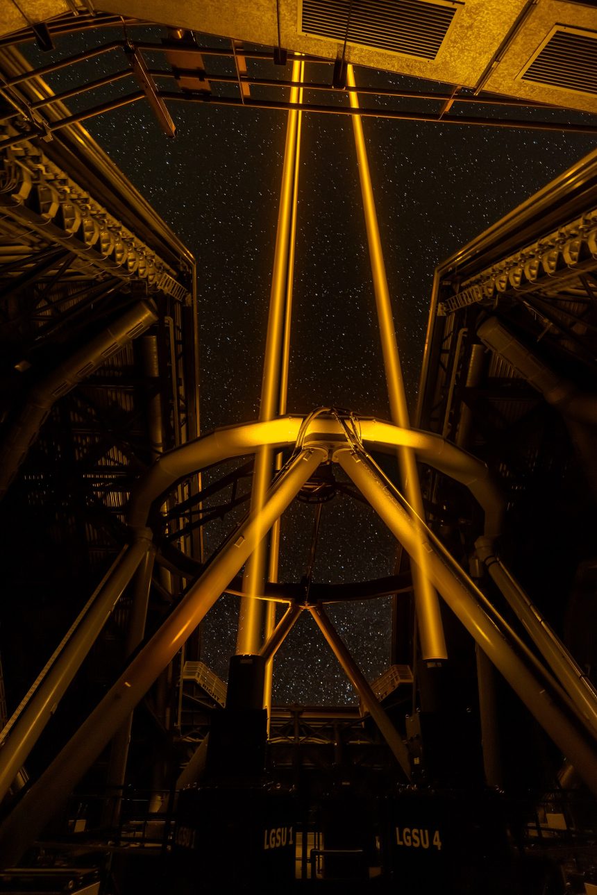 A telescope silhouetted against a star-filled night sky at an observatory